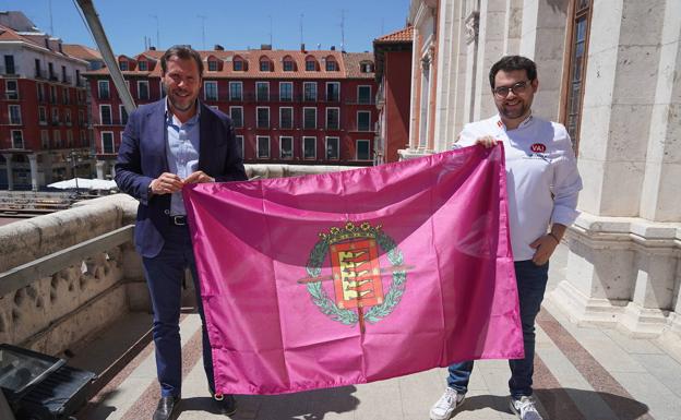 El alcalde, Óscar Puente, posa con una bandera de Valladolid en el balcón del Ayuntamiento, con el chef Alejandro San José. 