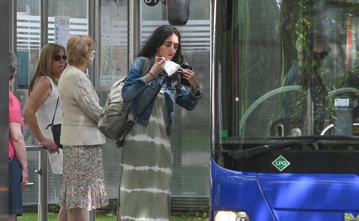 Una joven se coloca la marcarilla antes de entrar en un autobús. 