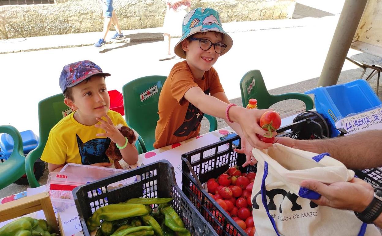 Los primos Leo y Gael, vendiendo a sus vecinos el excedente de productos de la huerta familiar 