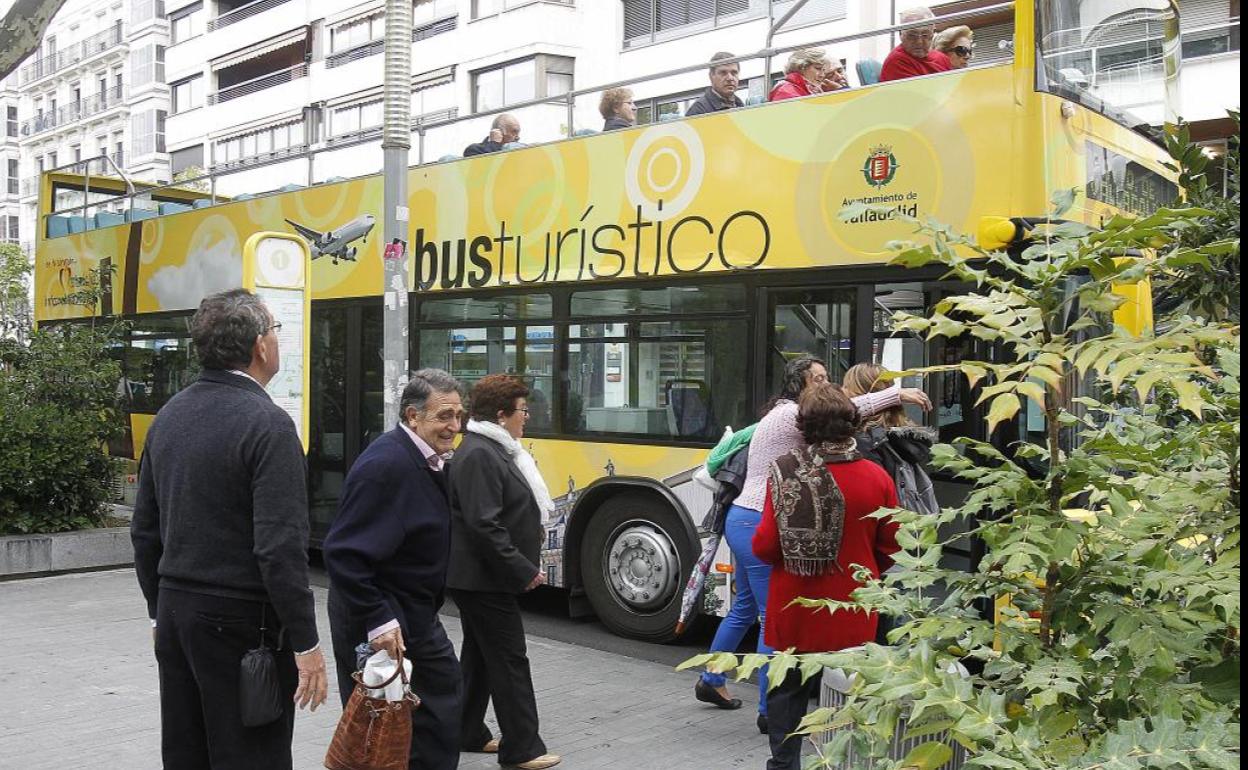 Un grupo de pasajeros hace cola para subir al bus turístico en la Acera de Recoletos.