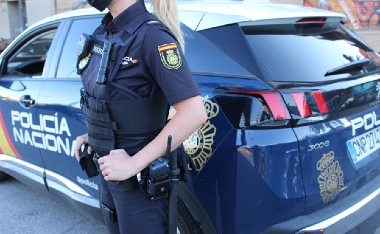 Fotografía de archivo de una agente de la Policía Nacional junto a su vehículo patrulla. 