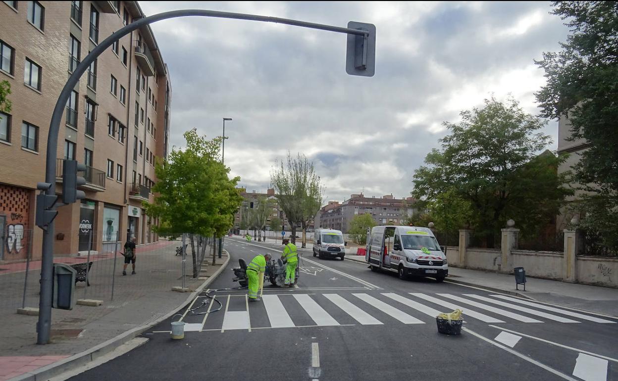 Los operarios rematan el pintado de las marcas viales en el paseo de Farnesio. 