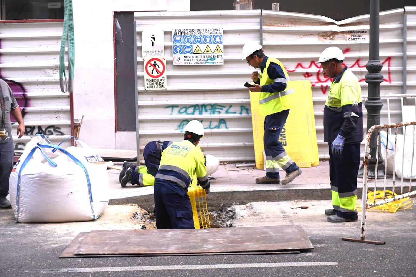 Varios operarios colocan una malla de refuerzo en la zanja donde esta noche se cayó con su moto.