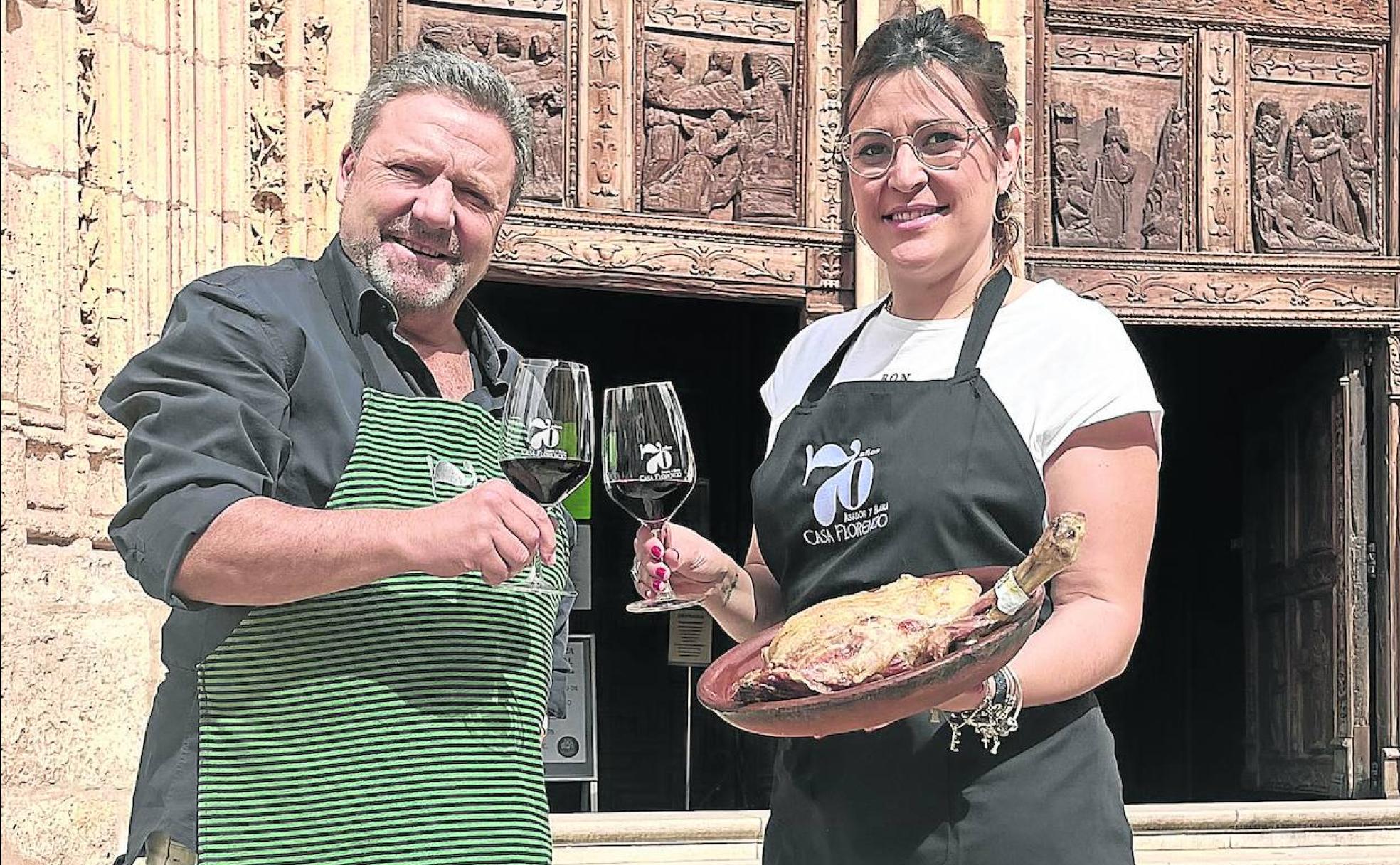 Rafael Miquel y Beatriz Barrusio, de Casa Florencio, brindan ante la portada de Santa María con los dos atributos representativos de Aranda: vino y lechazo asado. 