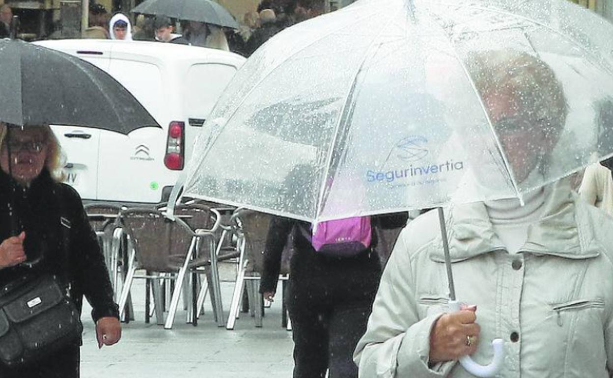 Transeúntes se protegen de la lluvia. 