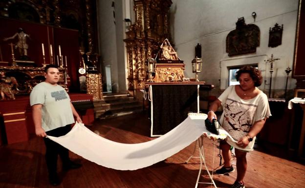 Dos cofrades de la La Pasión planchan un paño del templo. 