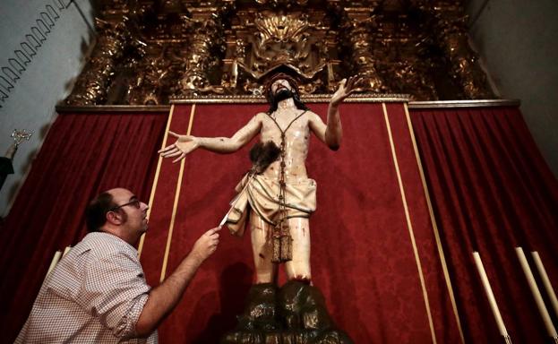 Un cofrade pasa el polvo con un plumero a una de las tallas procesionales con las que cuenta la hermandad. 