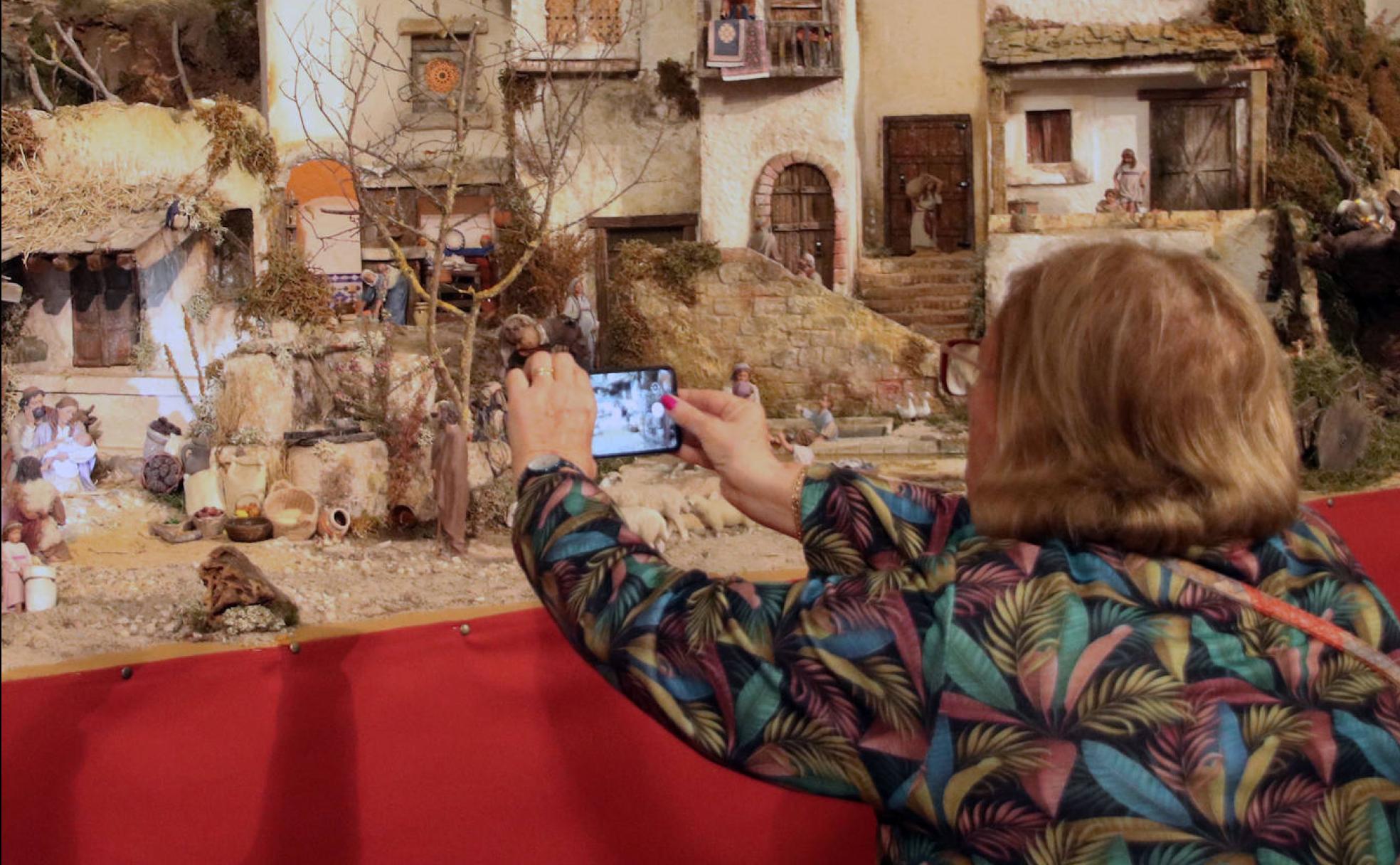 Una mujer saca una foto con el móvil a uno de los belenes expuestos estos días en Cuéllar. 