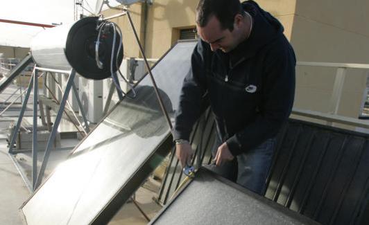 Un hombre instala una placa solar en un tejado.