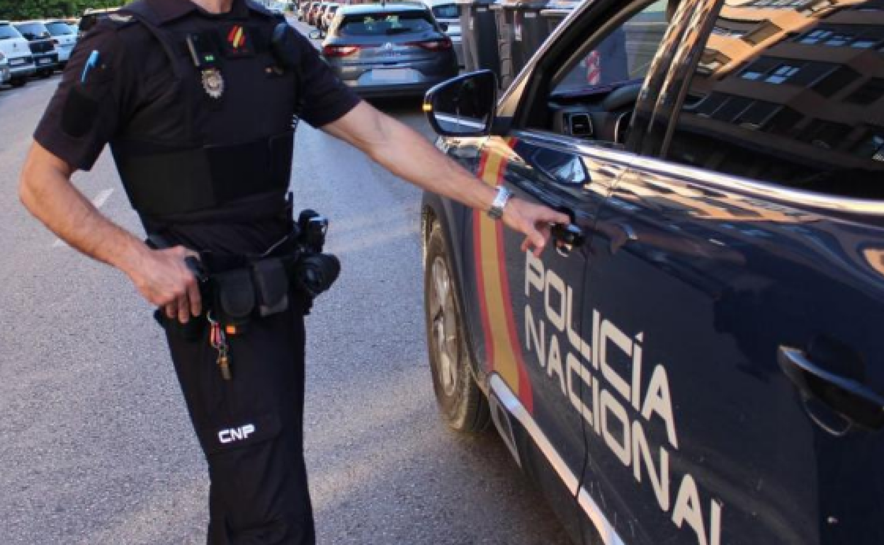 Imagen de un Policía Nacional junto a su vehículo. 