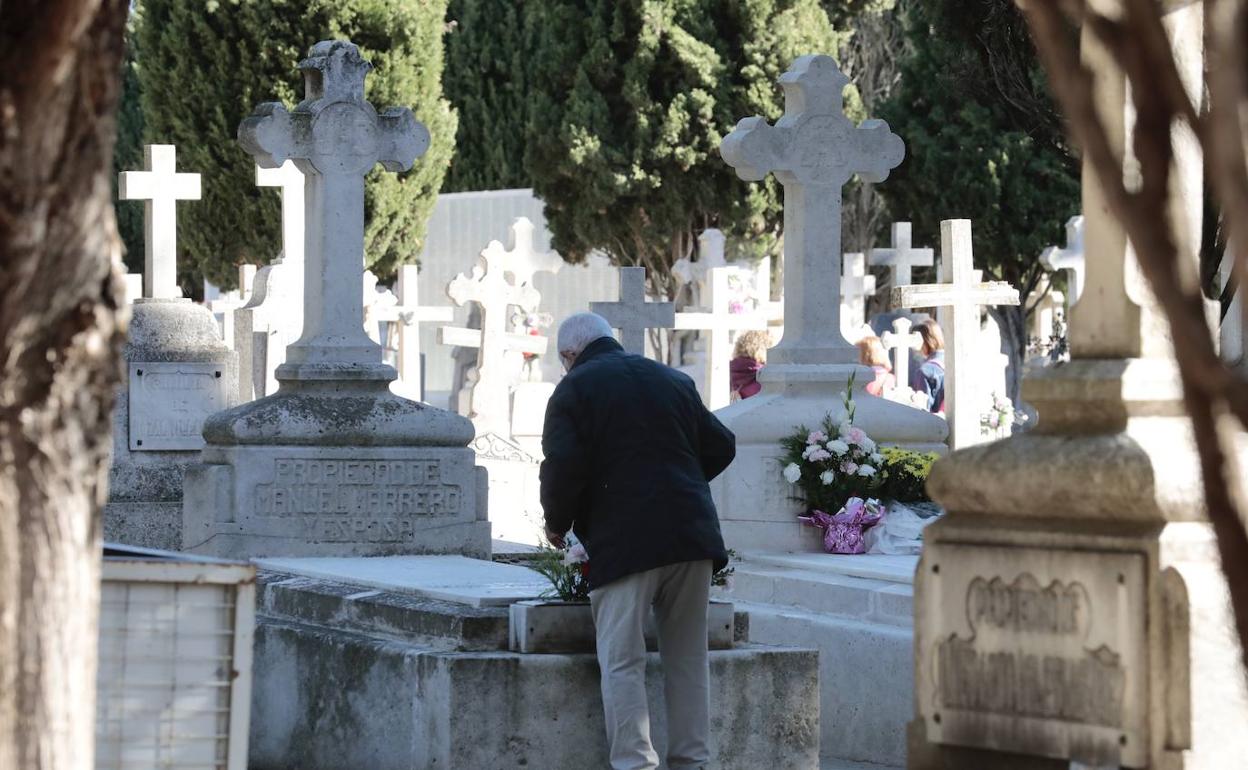 Un hombre coloca un ramo de flores en una sepultura del cementerio de El Carmen. 