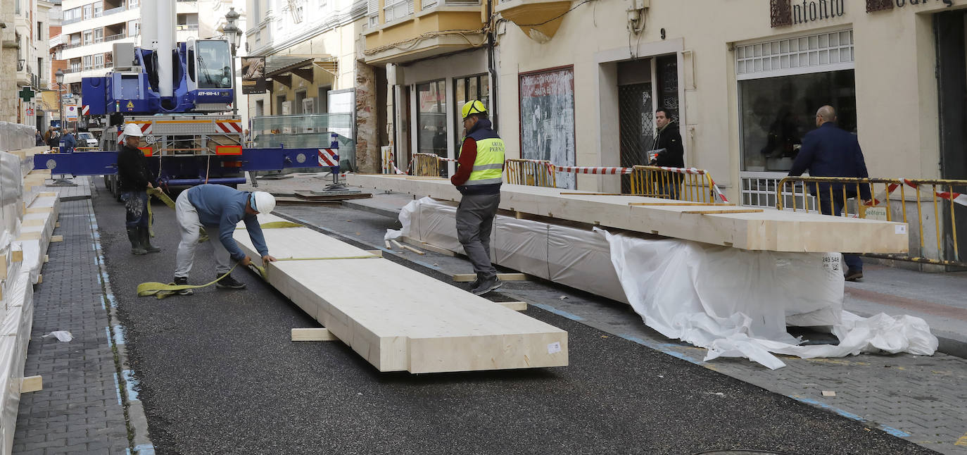 Una grúa de grandes dimensiones trabaja en la calle Burgos para colocar decenas de vigas de madera de tamaño gigante.