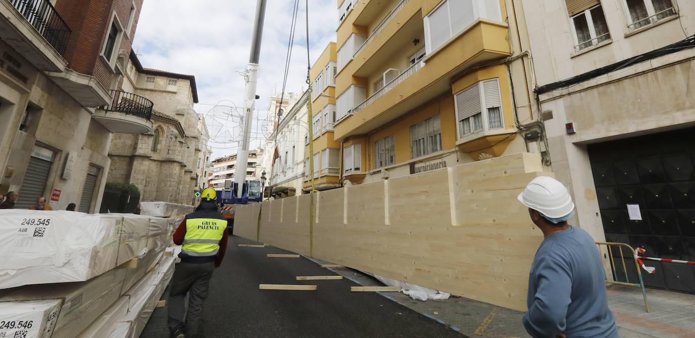 Una grúa de grandes dimensiones trabaja en la calle Burgos para colocar decenas de vigas de madera de tamaño gigante.