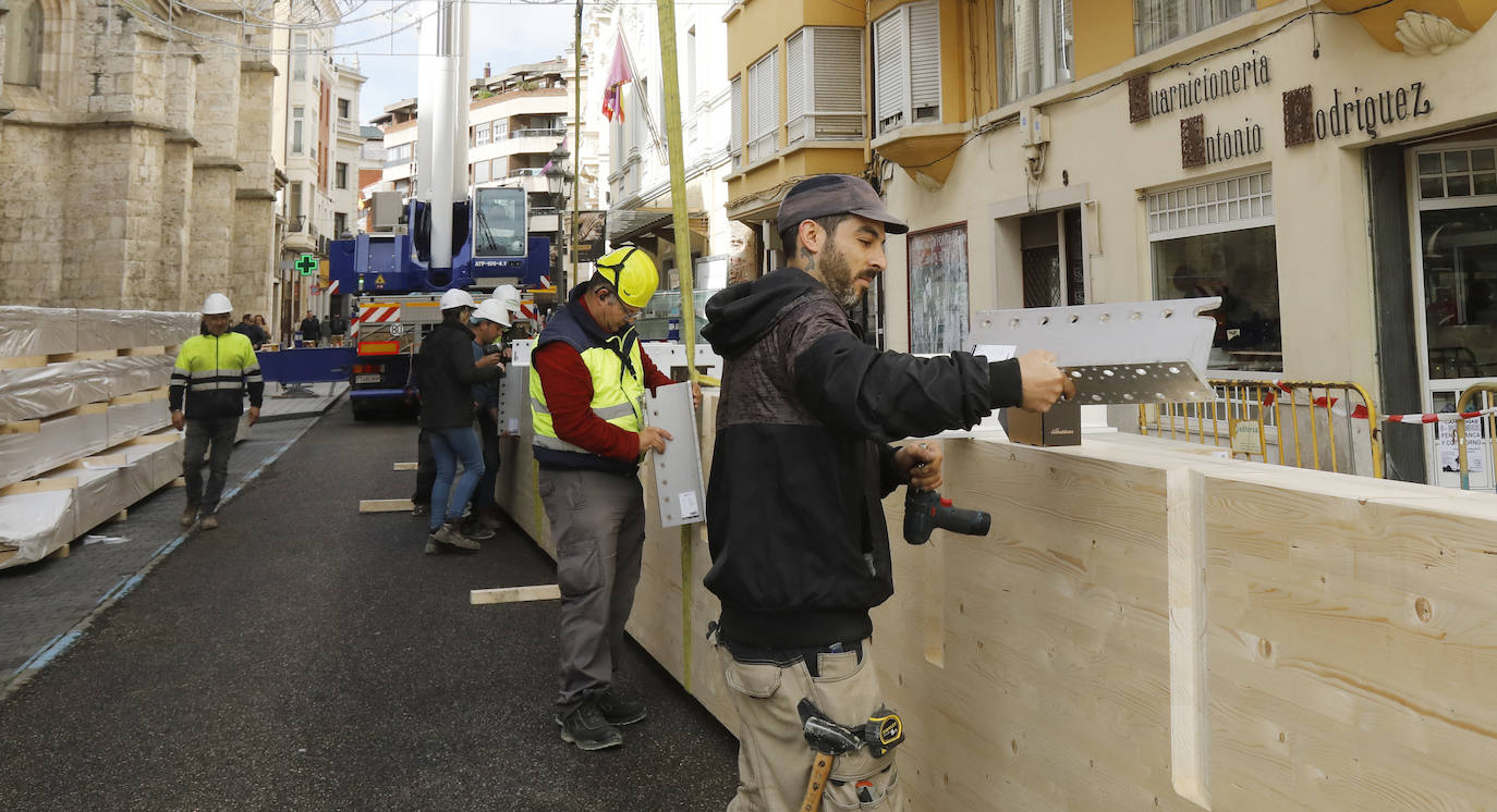 Una grúa de grandes dimensiones trabaja en la calle Burgos para colocar decenas de vigas de madera de tamaño gigante.