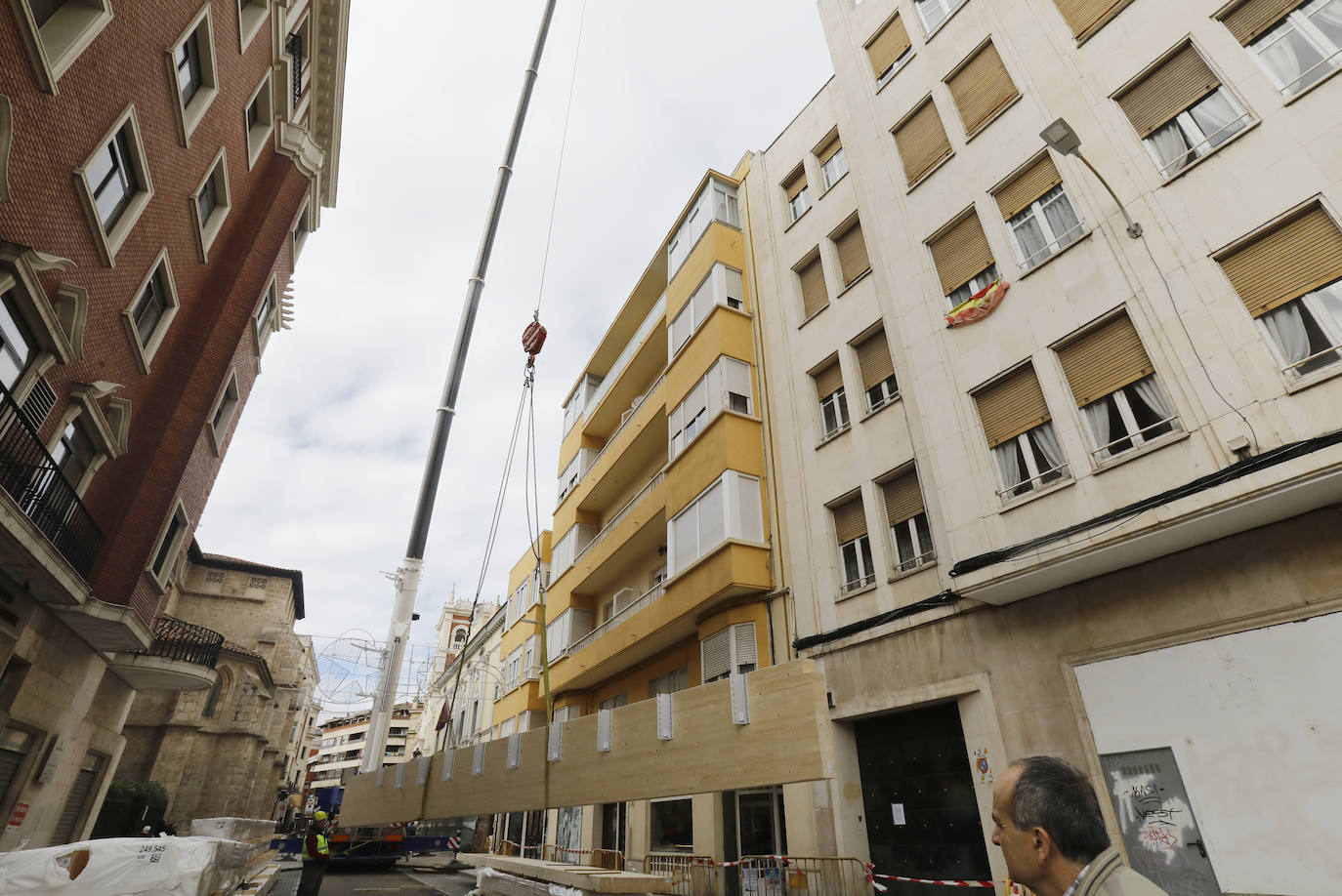 Una grúa de grandes dimensiones trabaja en la calle Burgos para colocar decenas de vigas de madera de tamaño gigante.