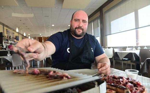 Sergio Rodríguez muestra su chuletón laminado y las parrillas individuales en las que cada cliente se cocina su carne al punto deseado 