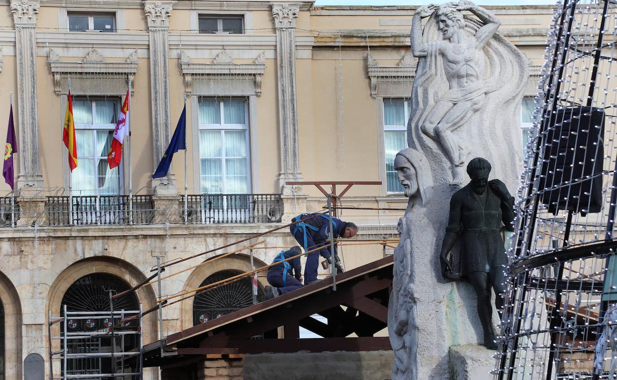 Dos operarios trabajan este martes en el tejado del portal de Belén de la Plaza Mayor.