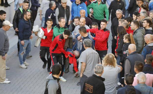 Varios vecinos trasladan al herido tras la cogida. 