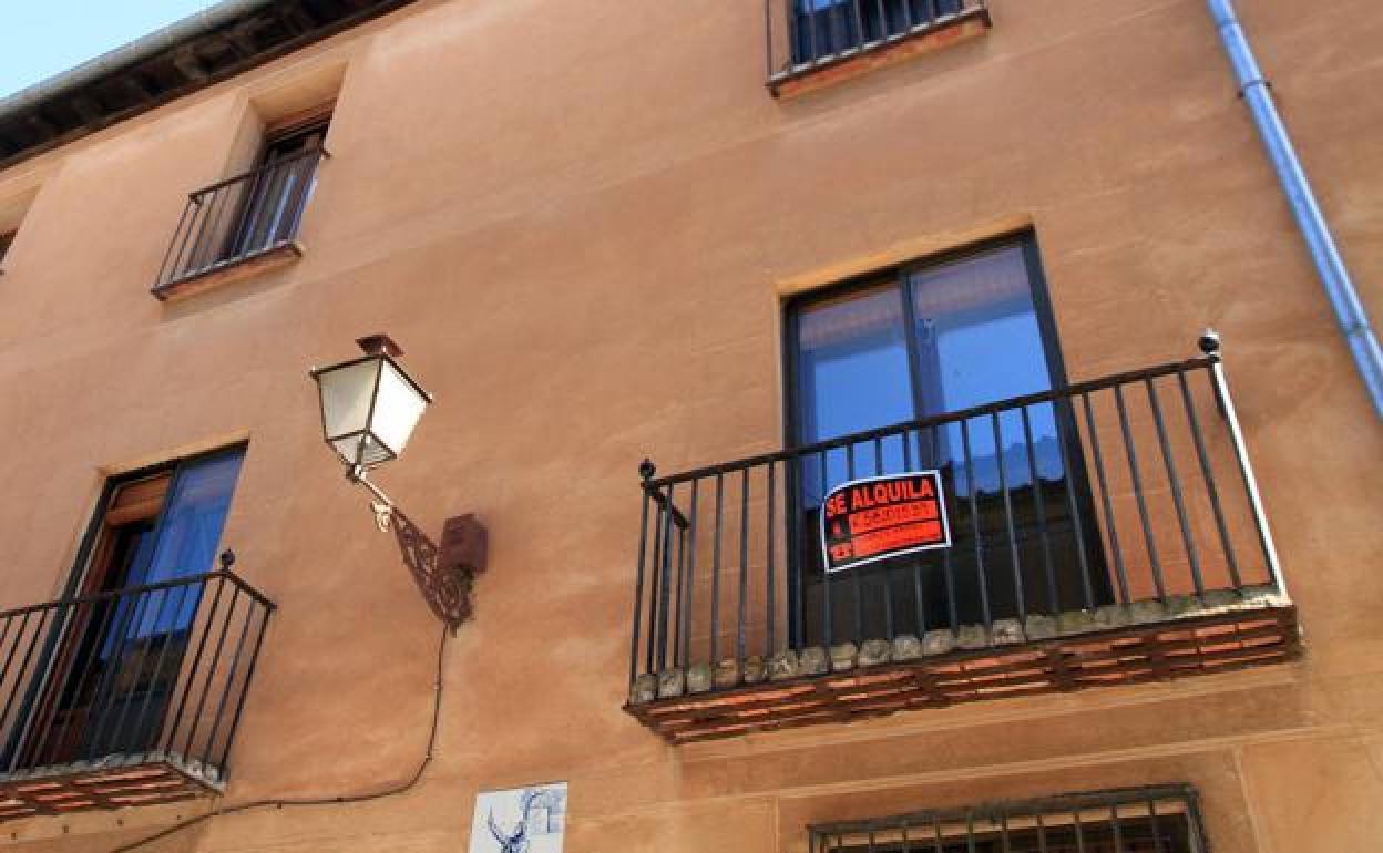 El balcón de una vivienda con un cartel que anuncia su alquiler. 