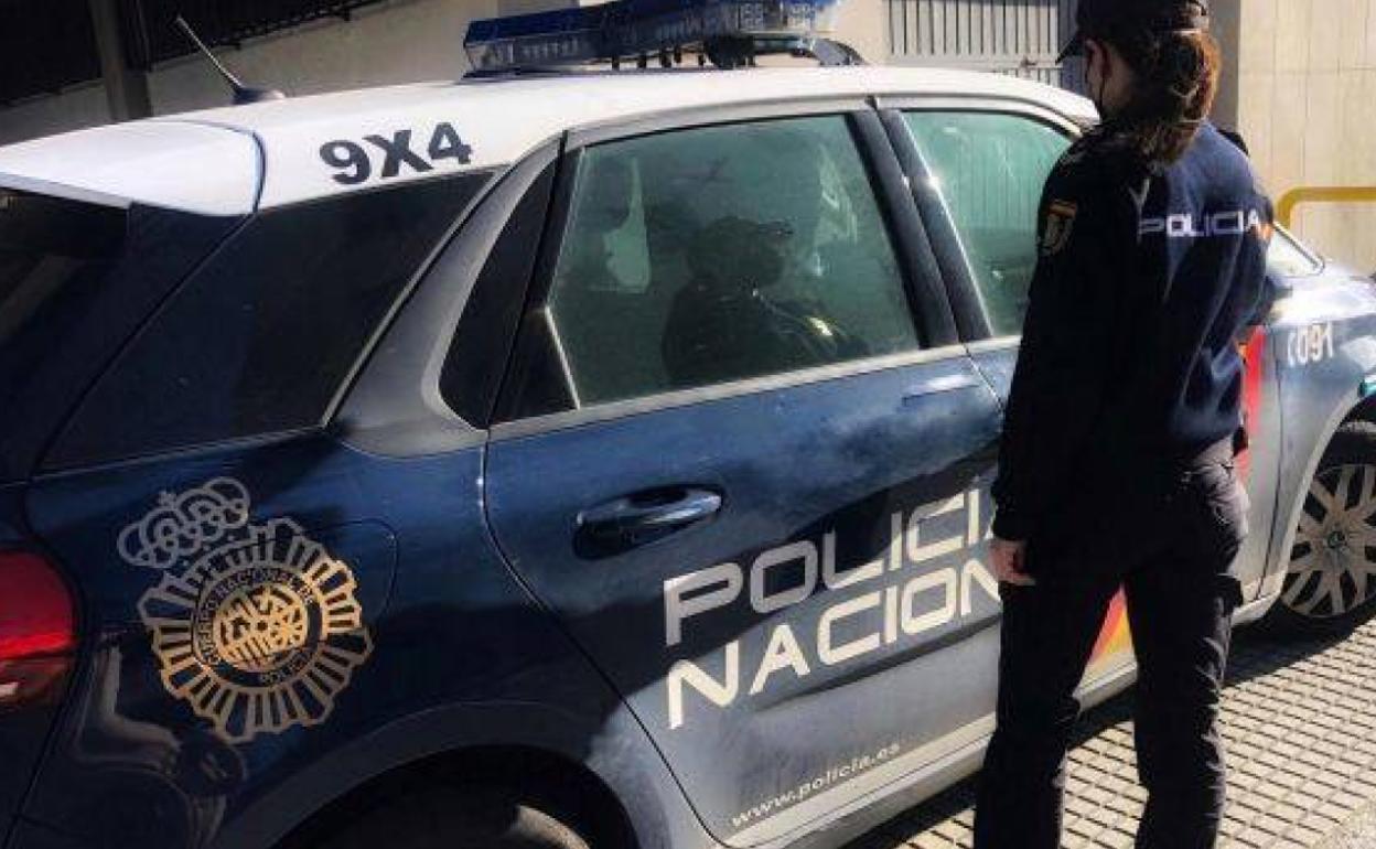 Una agente de la Policía Nacional junto a un vehículo patrulla.