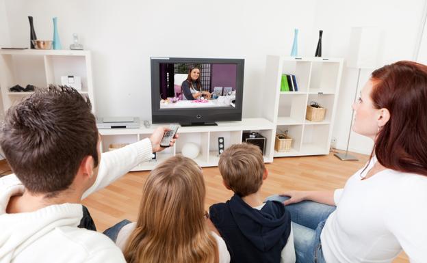 Familia viendo la televisión en el salón de su casa 