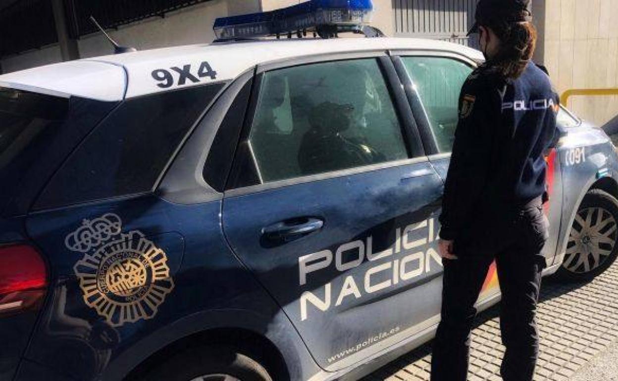 Una agnete de la Policìa Nacional junto a un coche patrulla. 