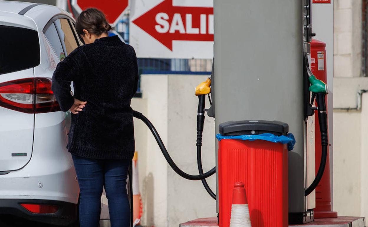 Una conductora llena el depósito del vehículo en una gasolinera. 