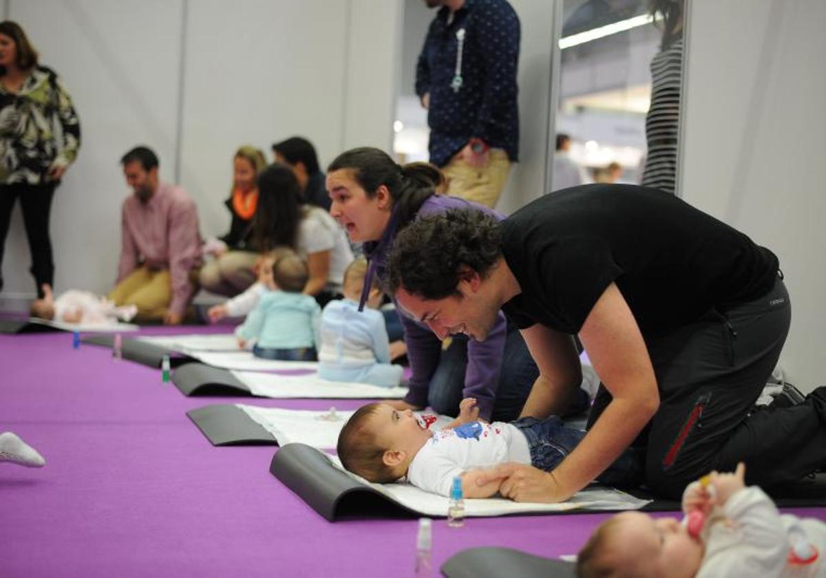 Padres y madres participan junto a sus hijos en una clase para conocer los cuidados de los bebés.