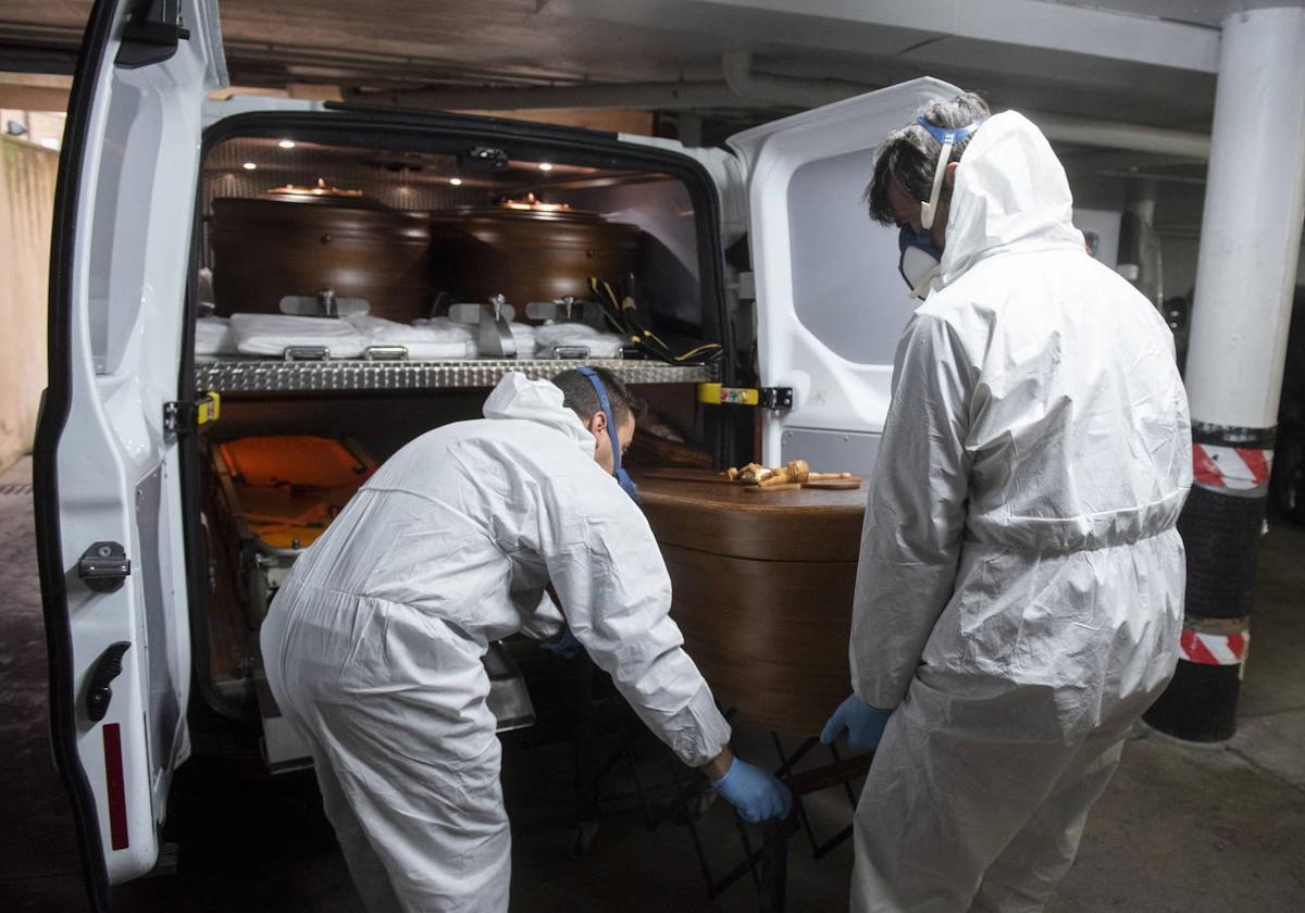 Empleados del servicio funerario introducen un féretro en un vehículo durante la pandemia en Segovia.