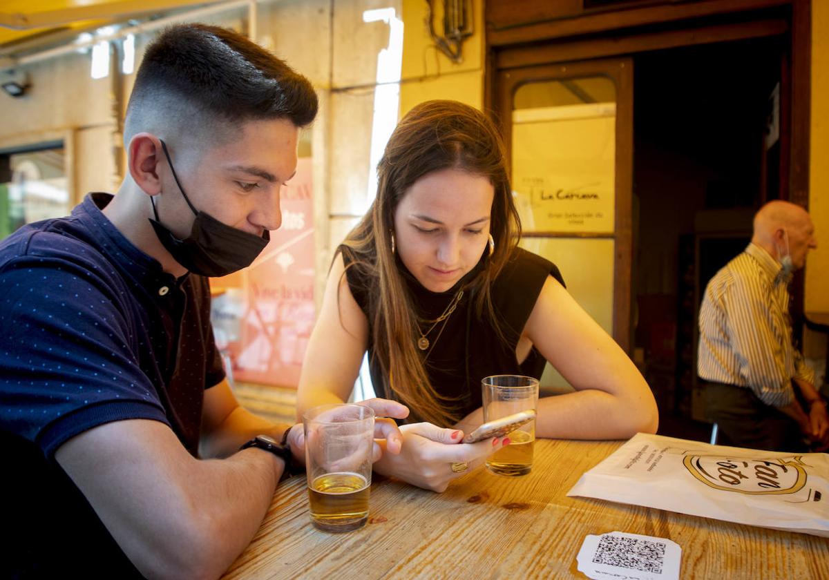 Dos jóvenes utilizan el móvil en un restaurante de Valladolid.