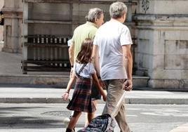 Dos adultos acompañan a una niña al colegio.