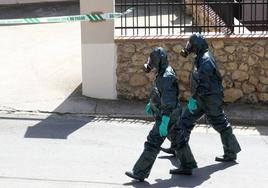 Dos efectivos con equipos de protección junto a la vivienda precintada en Carbonero de Ahusín.