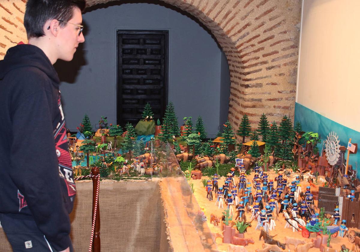 Un joven observa la exposición de Playmobil ambientada en el salvaje oeste.