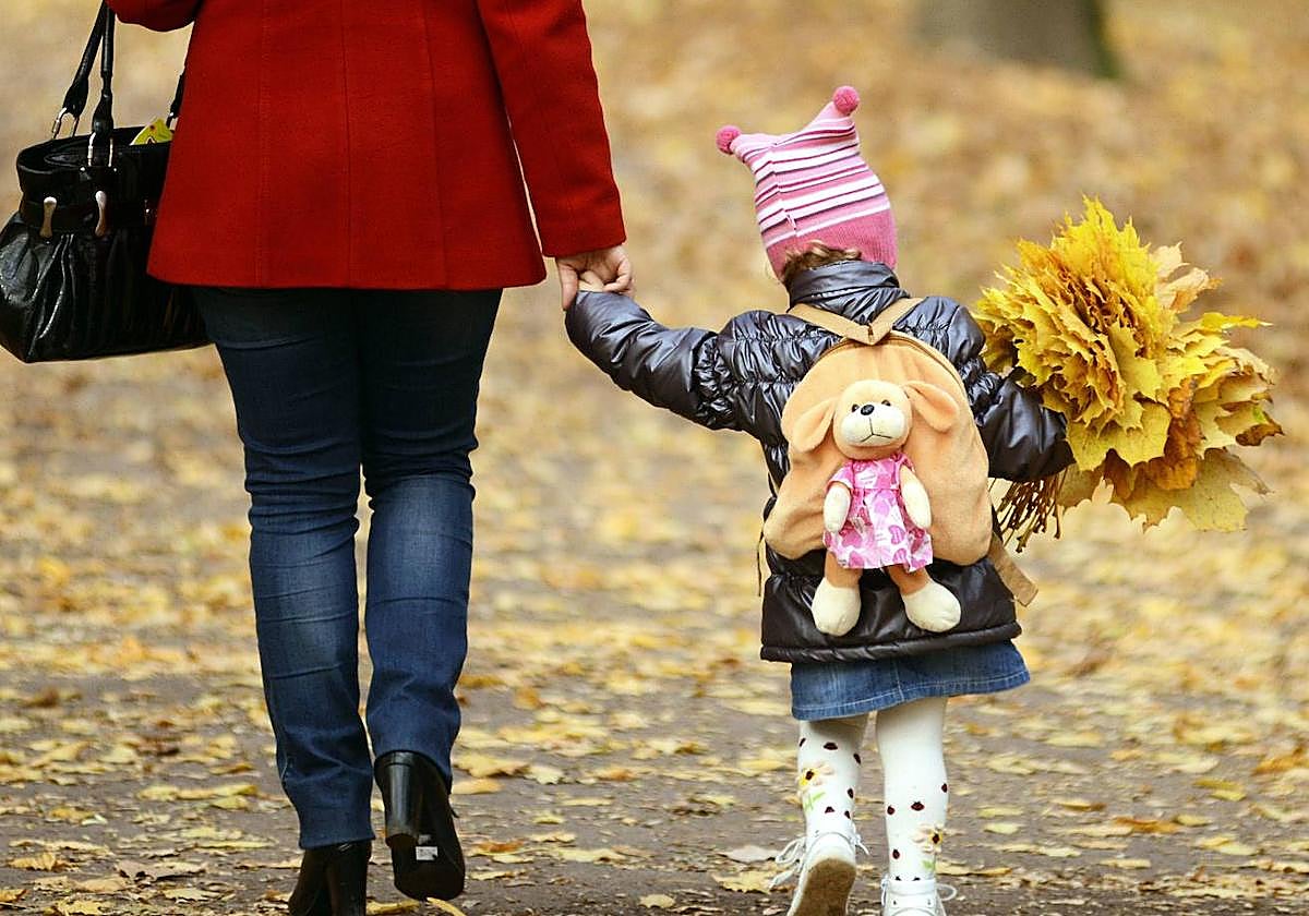 Una niña camina de la mano con su madre.