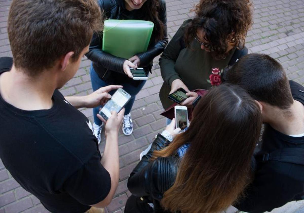 Un grupo de jóvenes consulta sus teléfonos móviles.