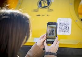 Una usuaria registra en su móvil el QR de un contenedor.