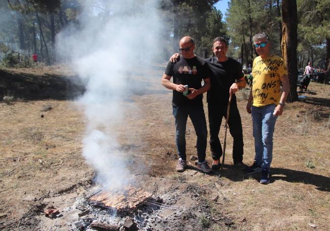 Asistentes a la carrera preparan unas viandas en las brasas en el pinar.