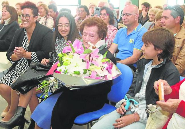 La homenajeada recibe un ramo de flores por su centenario.