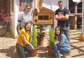 Noelia, Leticia (a la izquierda) y Cinthia, del AMPA de Villalón, y Alberto, el ebanista, posan con la nueva caseta para el intercambio de libros.