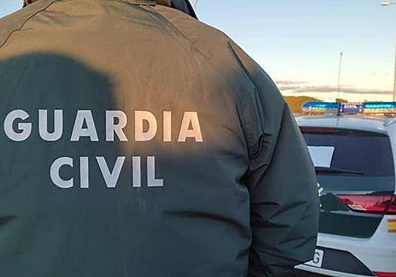 Un guardia civil delante de su coche patrulla.