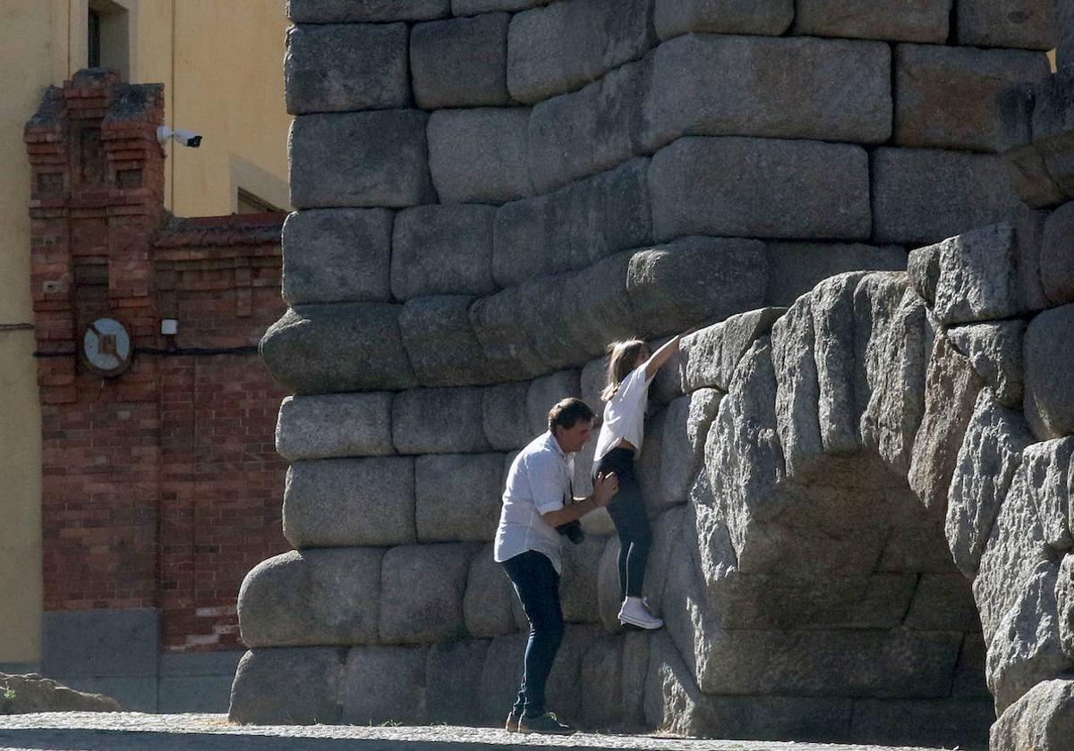 Un hombre ayuda a una joven a subir al Acueducto.