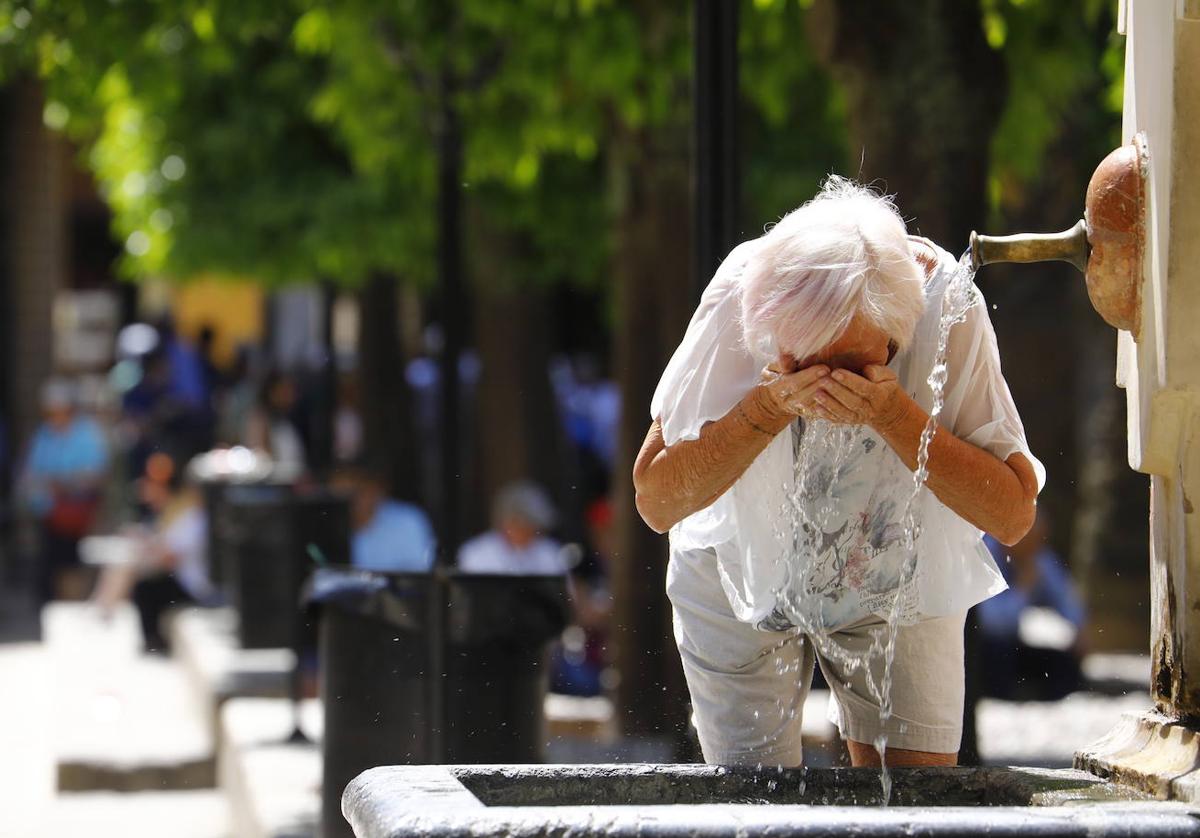 Una mujer se refresca y bebe agua para hacer frente al calor. EFE