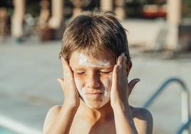 Imagen de archivo de un niño dándose protector solar.