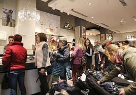 Clientes guardan cola para pagar en una tienda.