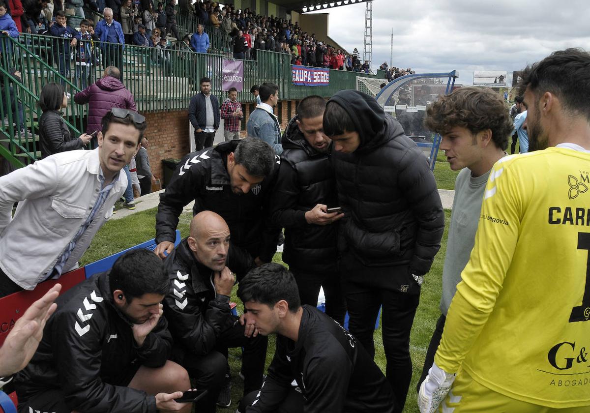 Cuerpo técnico y jugadores de la Segoviana siguen en sus teléfonos móviles los últimos minutos del partido en Alcorcón.