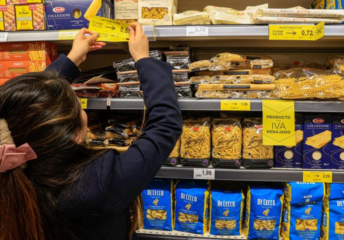 Una empleada de un supermercado cambia los carteles de los precios con la bajada del IVA.