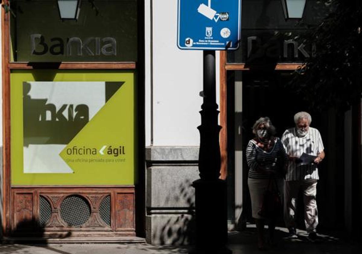 Dos personas caminan junto a una sucursal bancaria.