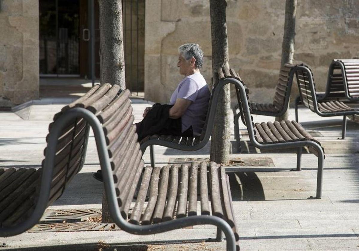 Una vecina mayor de Fermoselle, en Zamora, descansa en los bancos de una plaza.