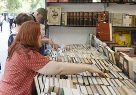 Varias personas observan ejemplares en uno de los puestos de la Feria del Libro Antiguo, este viernes en el Salón.