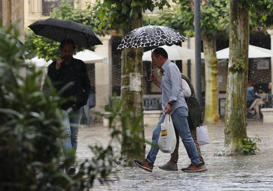 Los viandantes se protegen de la lluvia, este viernes en los entornos de la Plaza Mayor de Palencia.